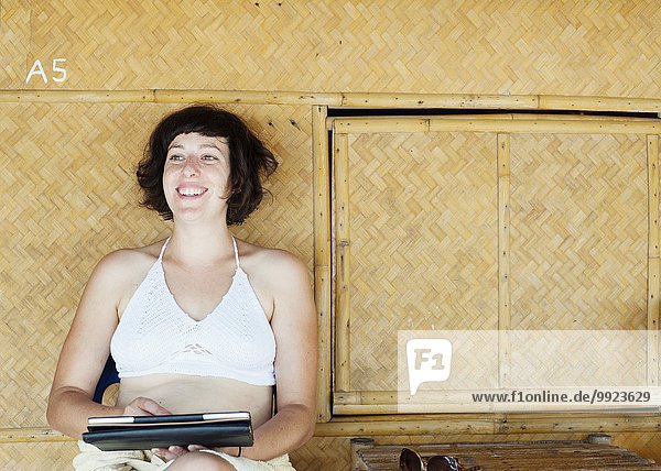 Frau mit digitalem Tablett vor der Strandhütte  Kradan  Thailand