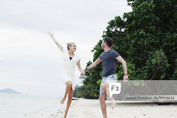 Junges Paar beim Springen und Toben am Strand  Kradan  Thailand