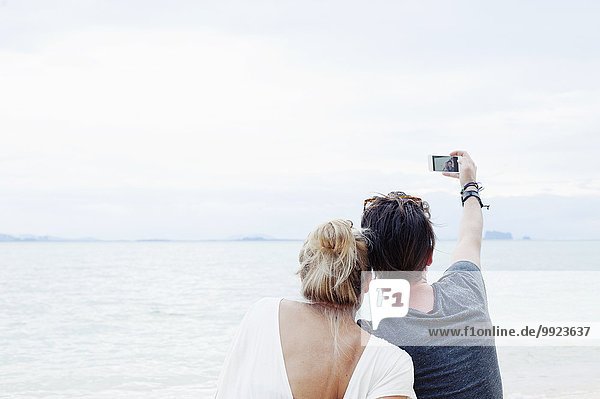 Rückansicht des jungen Paares mit Smartphone Selfie am Strand  Kradan  Thailand