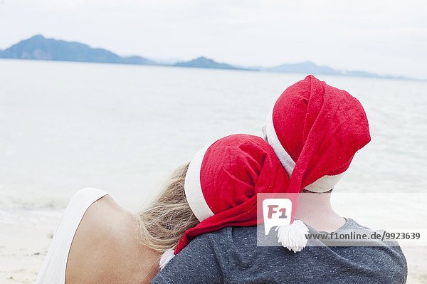 Rückansicht eines jungen Paares mit Weihnachtsmützen am Strand  Kradan  Thailand