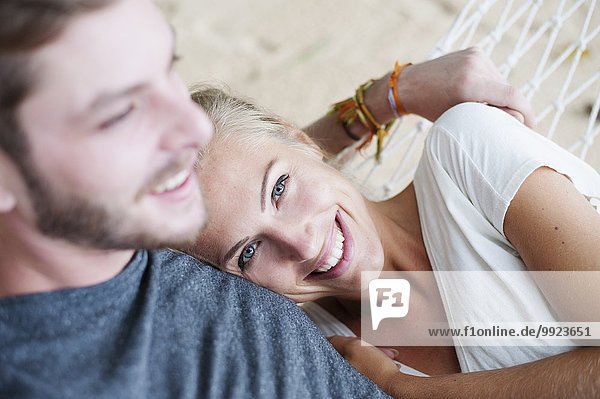 Nahaufnahme eines lächelnden jungen Paares auf einer Strandhängematte