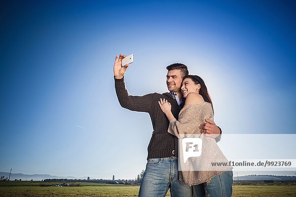 Junges Paar fotografiert sich gegen den blauen Himmel