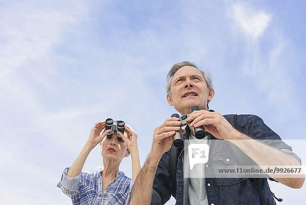 Senior couple watching birds with binoculars