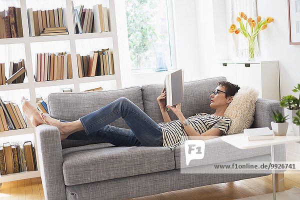 Senior woman reading book on sofa