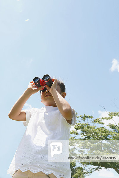Japanese young girl with binoculars in a city park