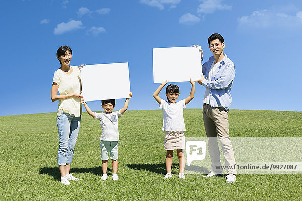 Happy Japanese family with whiteboards in a city park