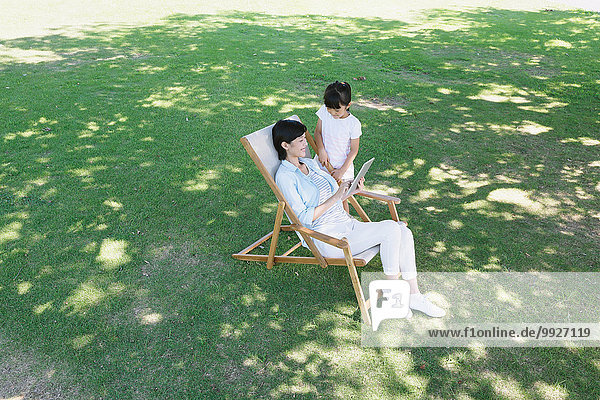 Japanese mother and daughter with tablet in a city park