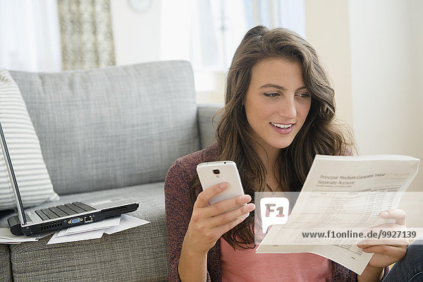 Woman in living room with papers and smartphone