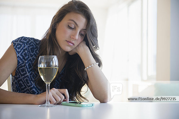 Sad woman with glass of wine texting