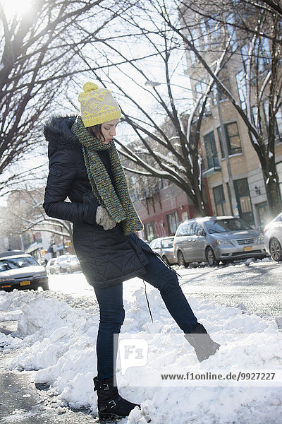 Woman in street putting her leg into snow