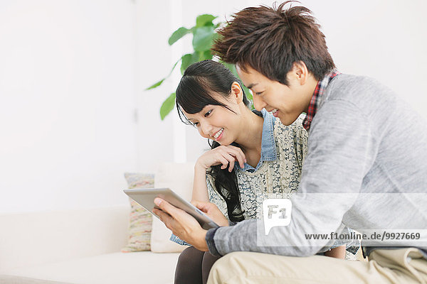 Young adult couple relaxing with tablet on the sofa