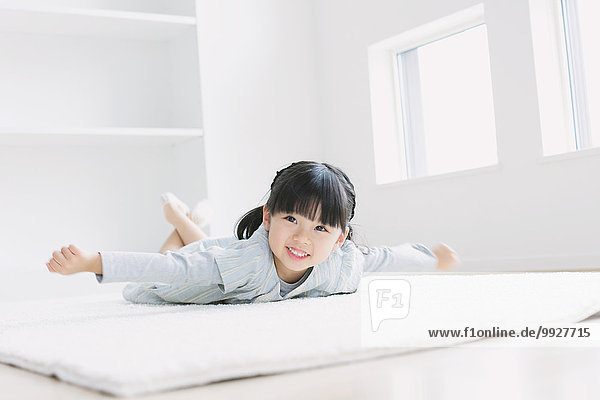 Elementary age girl laying on the floor by the window