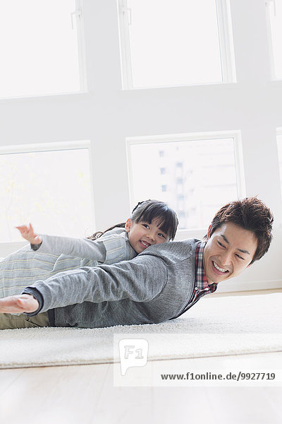 Elementary age girl laying on his fathers back and smiling