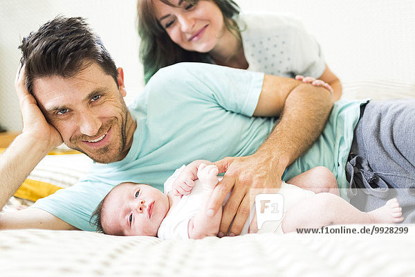 Happy parents with baby boy (6-11 months) lying on bed