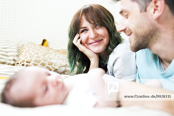 Happy parents with baby boy (6-11 months) on bed