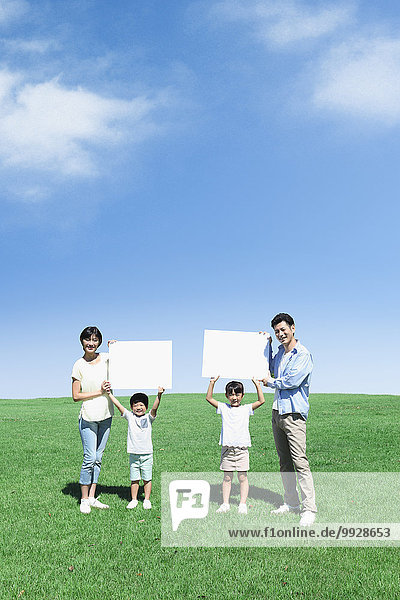 Happy Japanese family with whiteboards in a city park