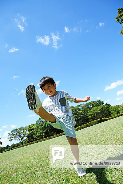 Japanese young boy playing soccer in a city park
