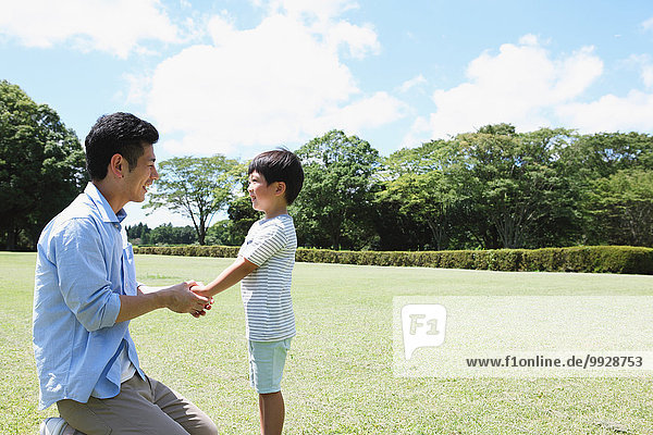 Happy Japanese father and son in a city park