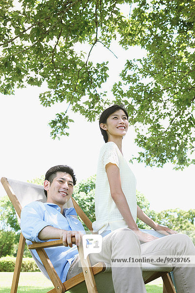Happy Japanese couple with deck chair in a park