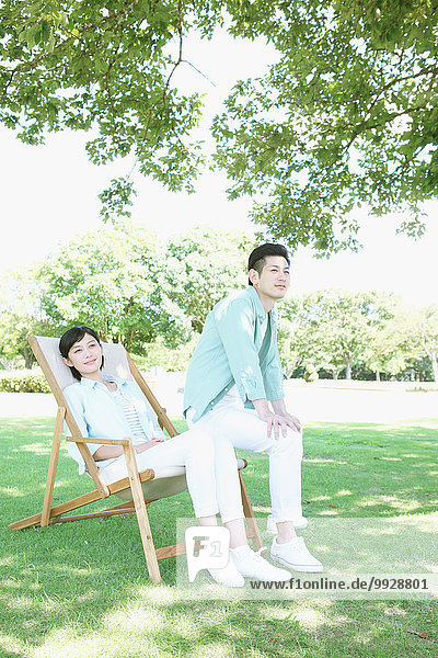 Happy Japanese couple with deck chair in a park