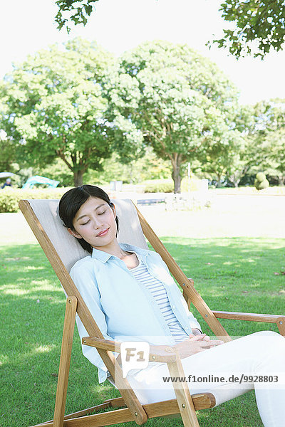 Japanese woman resting on deck chair in a city park