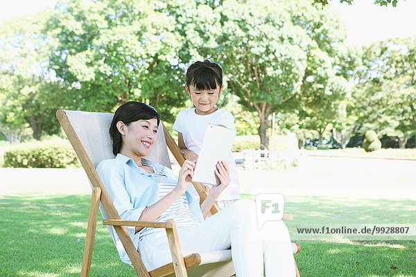 Japanese mother and daughter with tablet in a city park