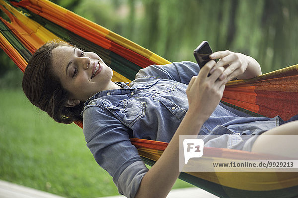 Woman relaxing in hammock with smartphone