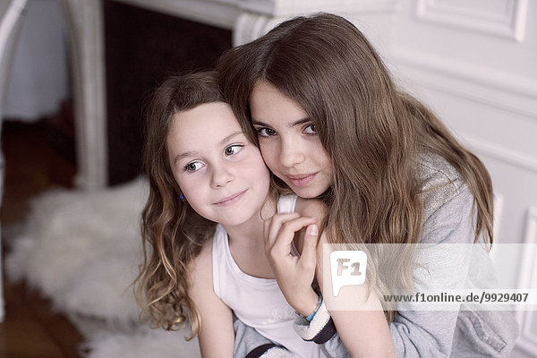 Mädchen umarmt jüngere Schwester  Portrait