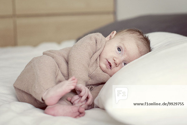 Newborn baby lying on bed  looking up