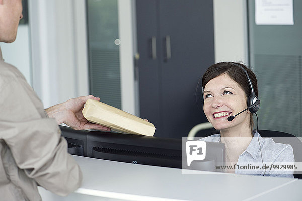 Receptionist receiving package from delivery person