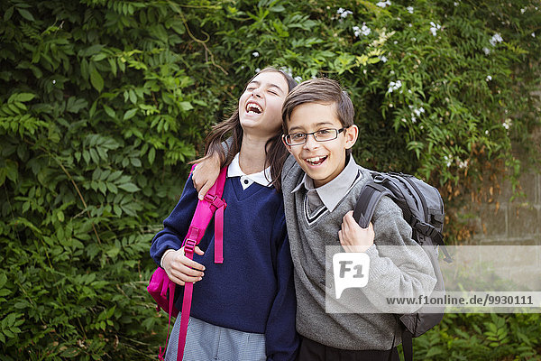 Mixed race brother and sister laughing in school uniforms