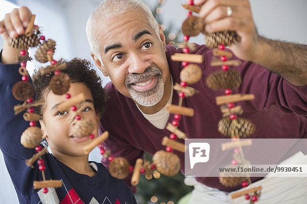 Mixed race grandfather and grandson holding Christmas decorations