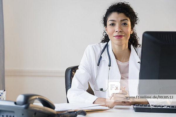 Mixed race doctor sitting at desk in office