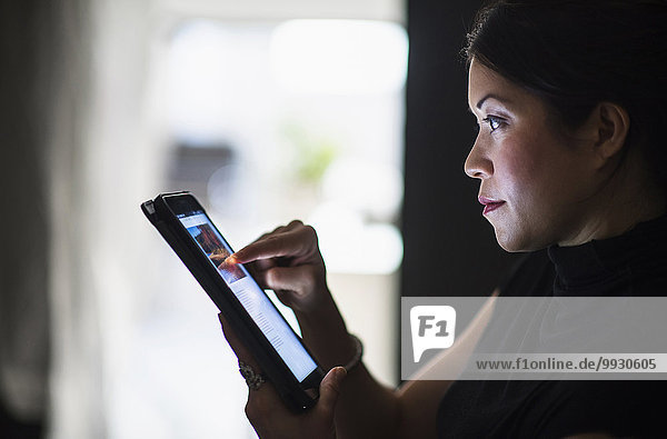Mixed race woman using digital tablet at night