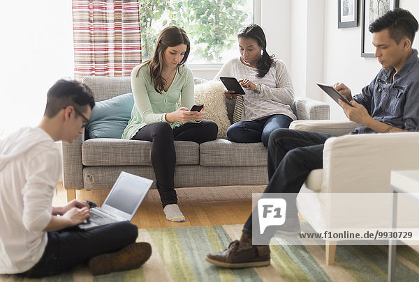 Friends using technology in living room