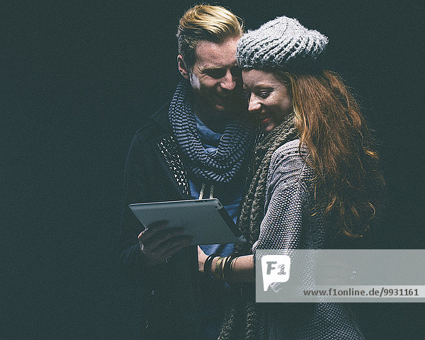 Couple wearing warm clothing using digital tablet