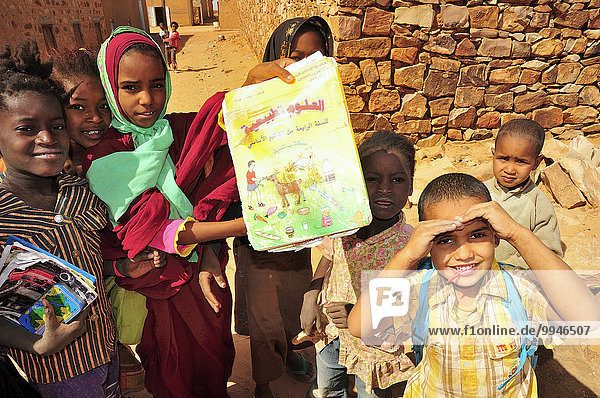 Kinder zeigen ein Schulbuch  Ouadane  Region Adrar  Mauretanien  Afrika
