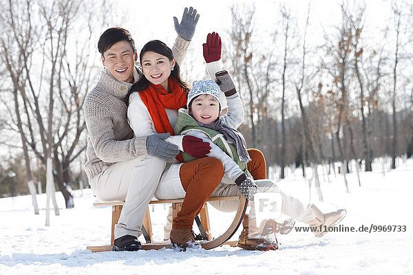 The happiness of a family of three sitting on a sled