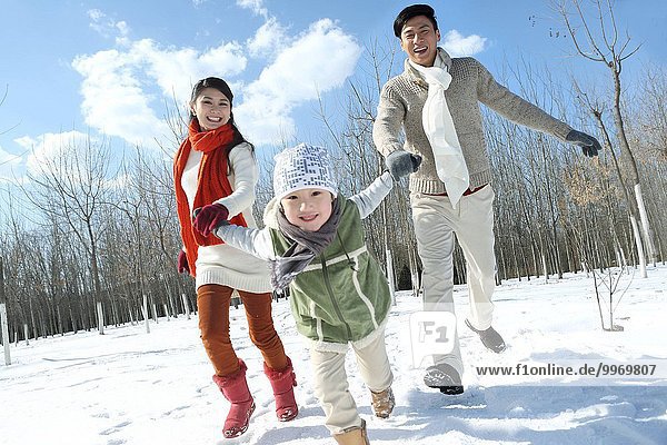 A family of three running in the snow