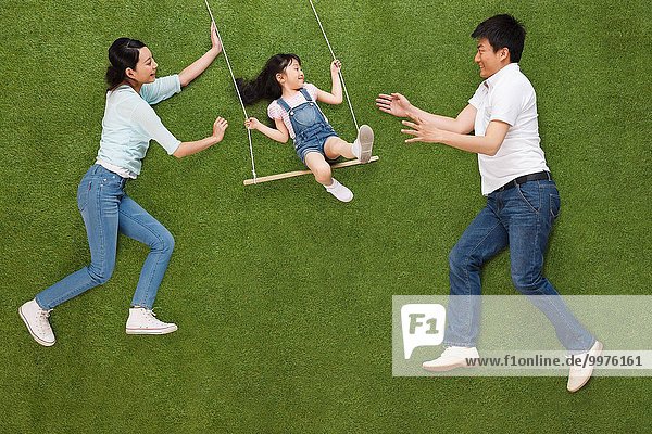 The happiness of a family of three swing on the grass