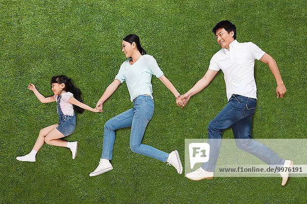 A family of three lying on the grass do running posture