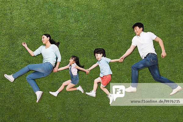 A family of four lying on the grass do running posture