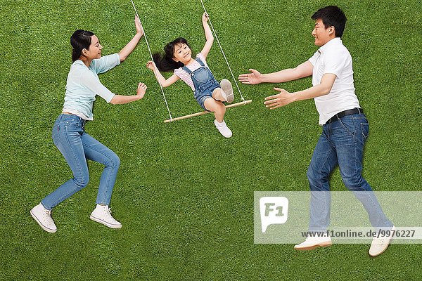 The happiness of a family of three swing on the grass