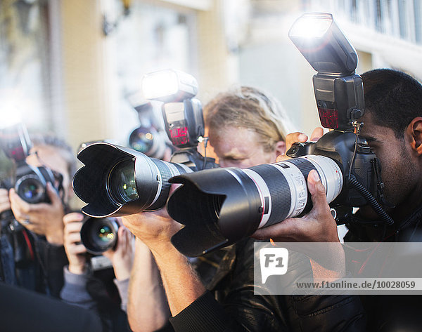 Close up of paparazzi photographers pointing cameras at event