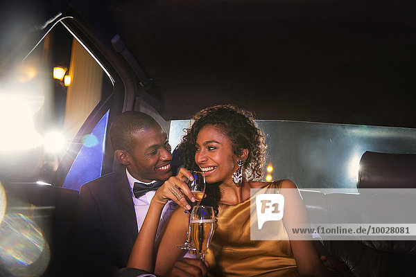 Celebrity couple drinking champagne inside limousine outside event