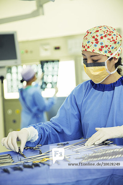 Surgeon arranging surgical scissors on tray in operating room
