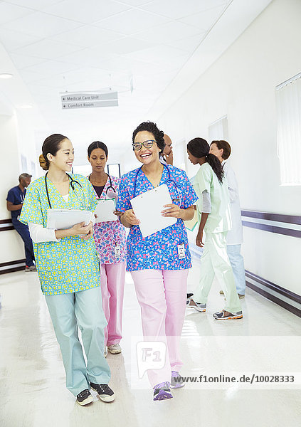Smiling nurses talking and walking in hospital corridor