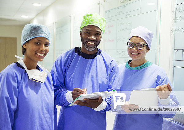 Portrait von lächelnden Chirurgen mit Klemmbrettern im Krankenhaus
