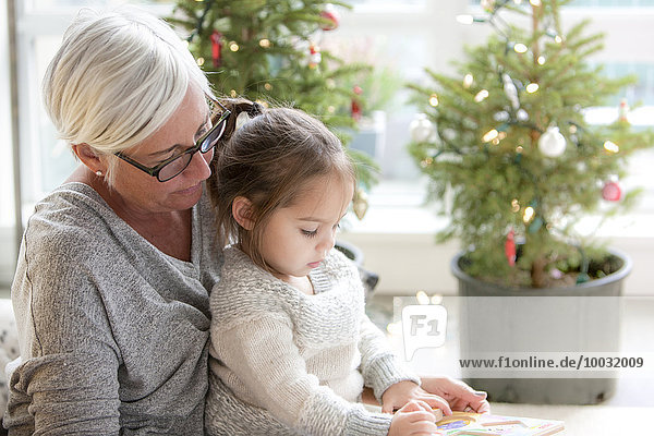 Großmutter beim Zeichnen der Enkelin vor den Weihnachtsbäumen