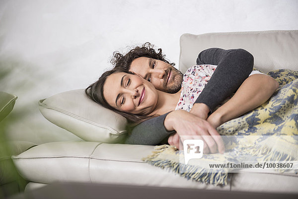Mid adult couple sleeping on sofa  Munich  Bavaria  Germany